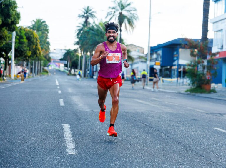 Athlete in vibrant attire competing in a city marathon on a sunny day.